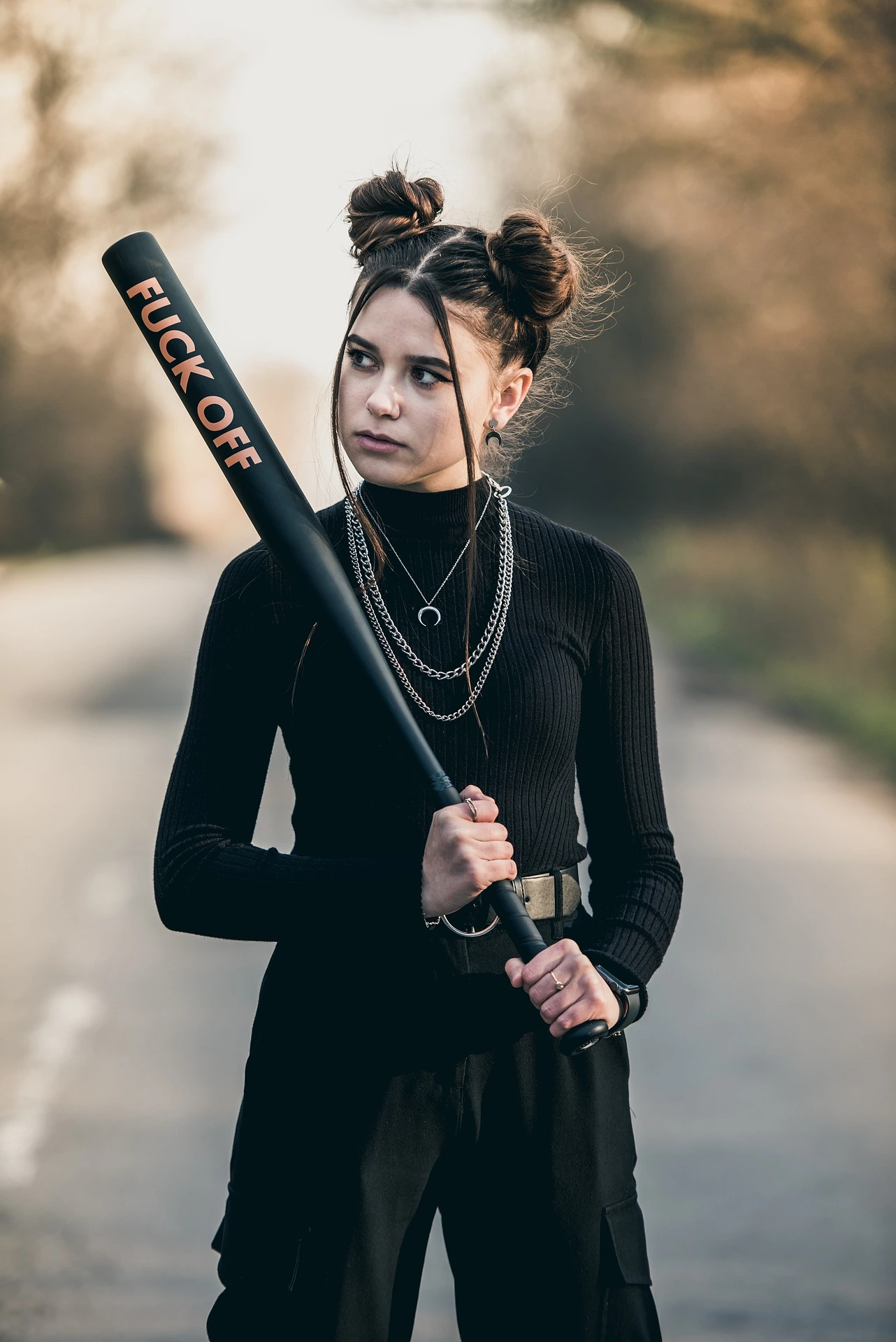 Eine dunkel gekleidete, wütende Frau mit einem Baseballschläger in den Händen.