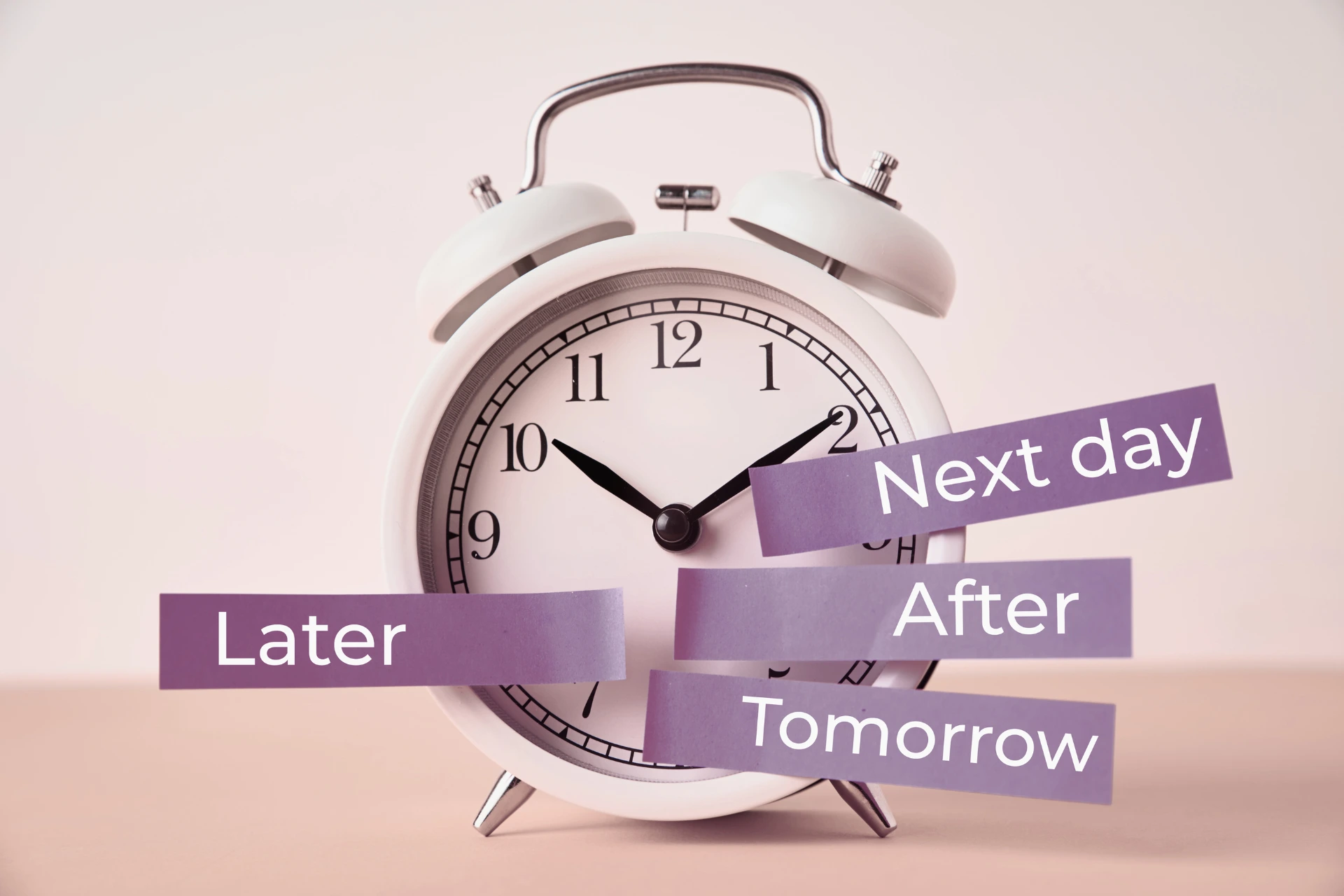 Ein Wecker an dem verschiedene Aufkleber kleben mit der Aufschrift 'later', 'tomorrow', 'after' und 'next day'.