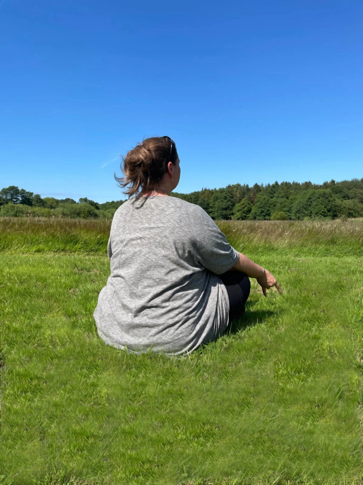 Eine Frau auf einer Wiese, die meditiert.
